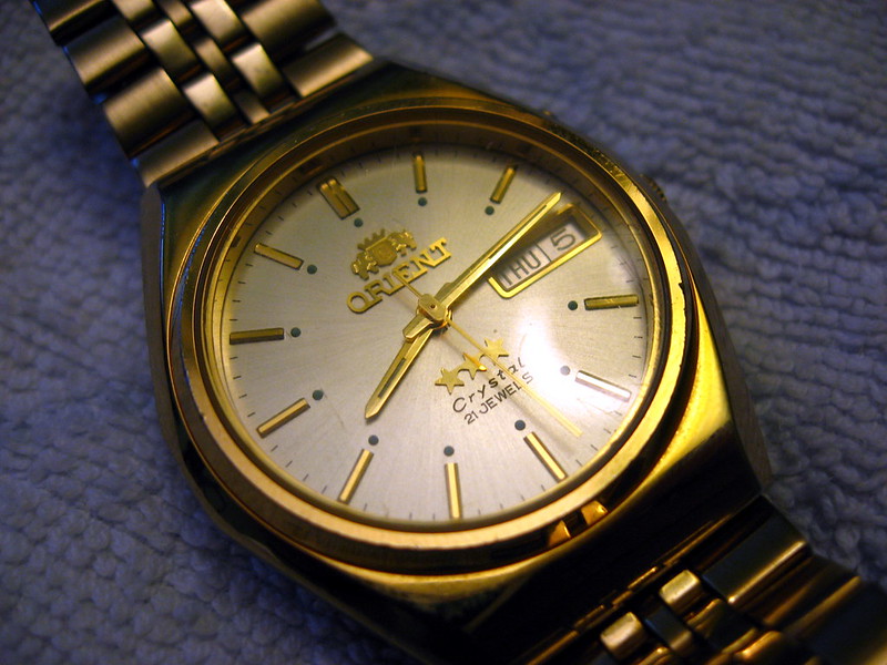 orient gold watch in blue background